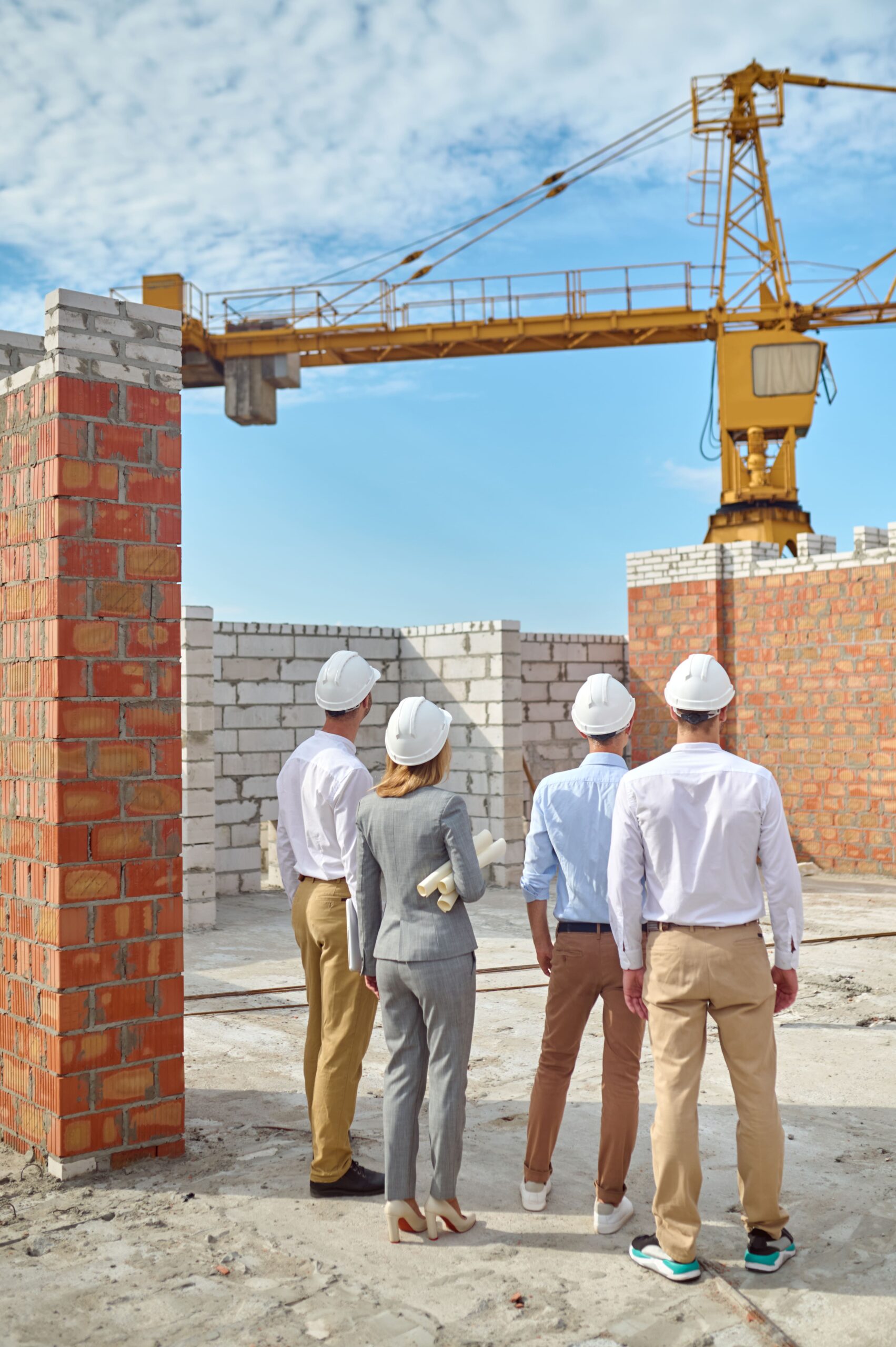 four-people-protective-helmets-inspecting-building-area-min